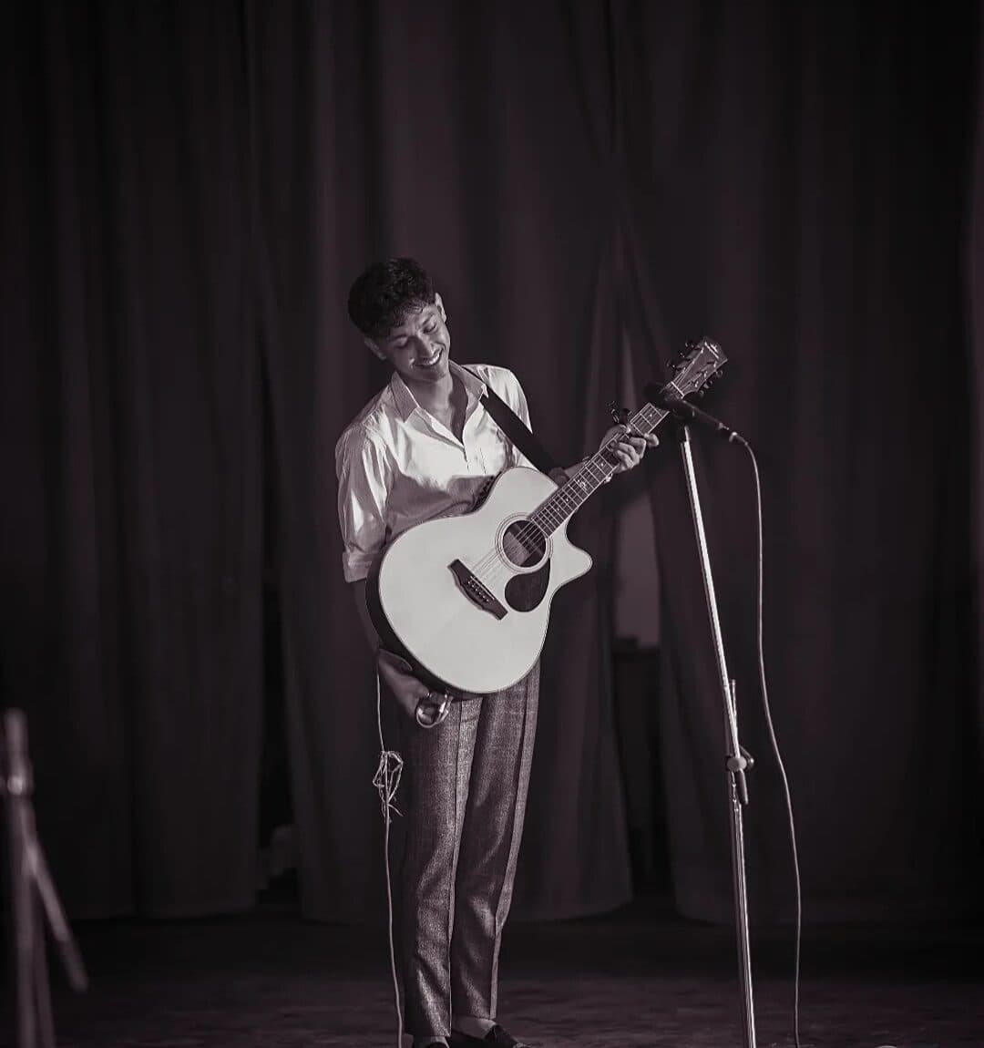 Deepak playing acoustic guitar on stage