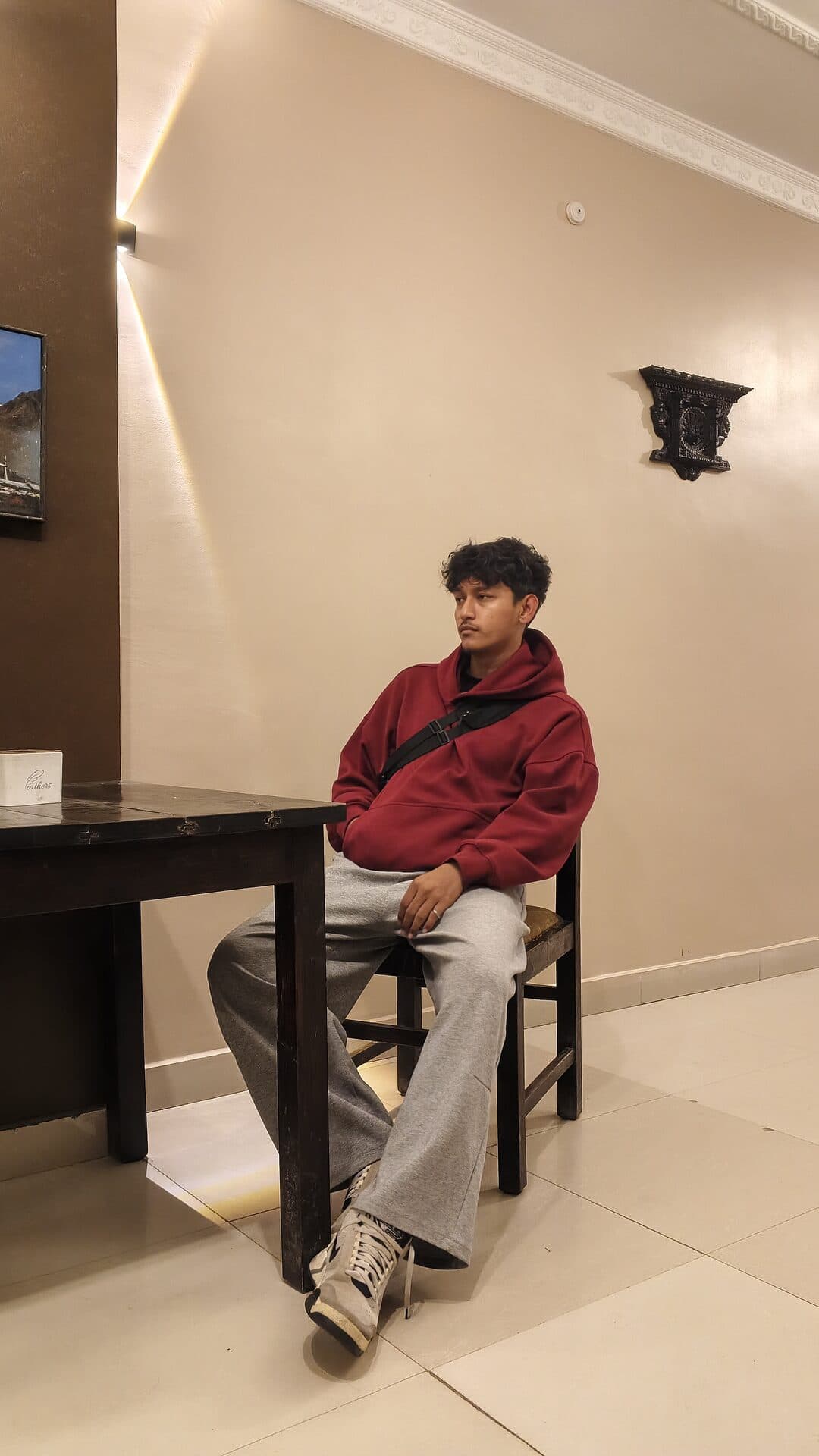 Deepak in a red hoodie, seated at a café table