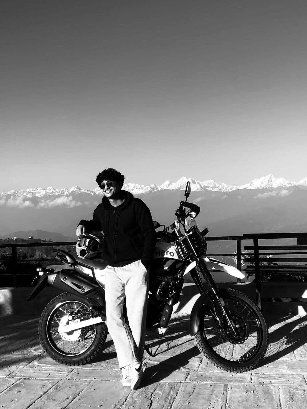 Deepak leaning on a motorbike with the Himalayan range behind him